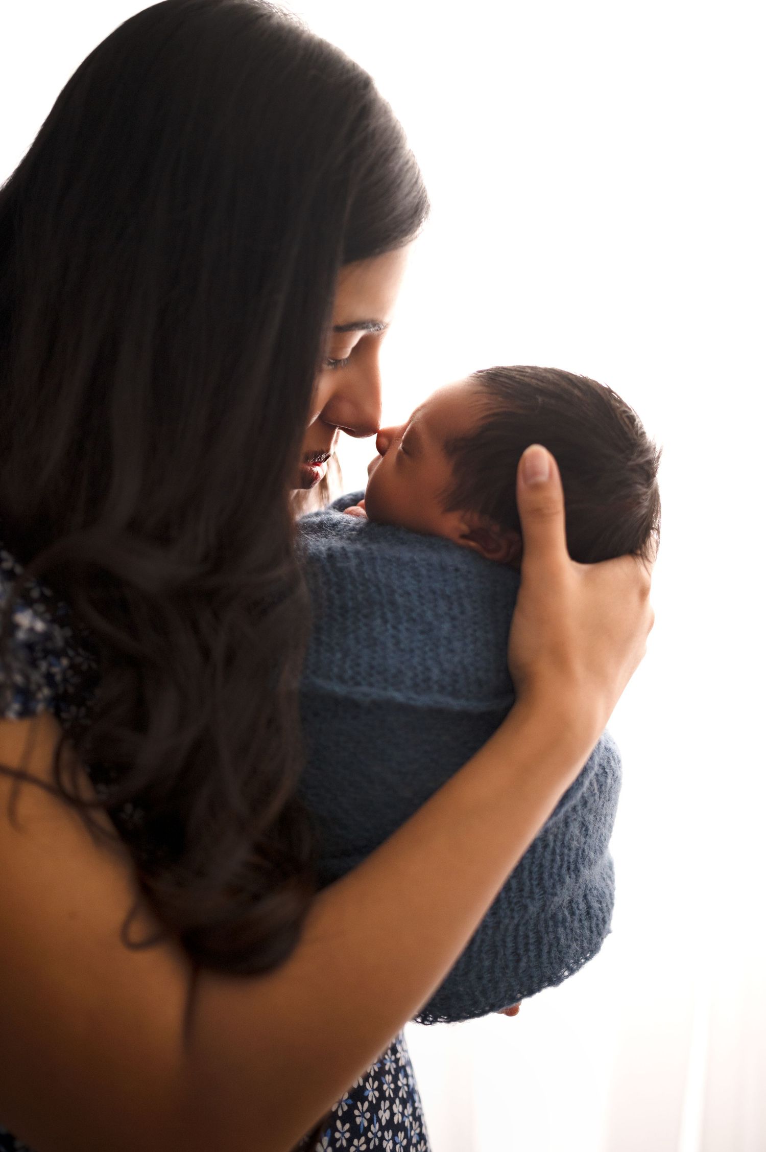 Artistic silhouette images capturing tender family moments with newborn in blue wrap.