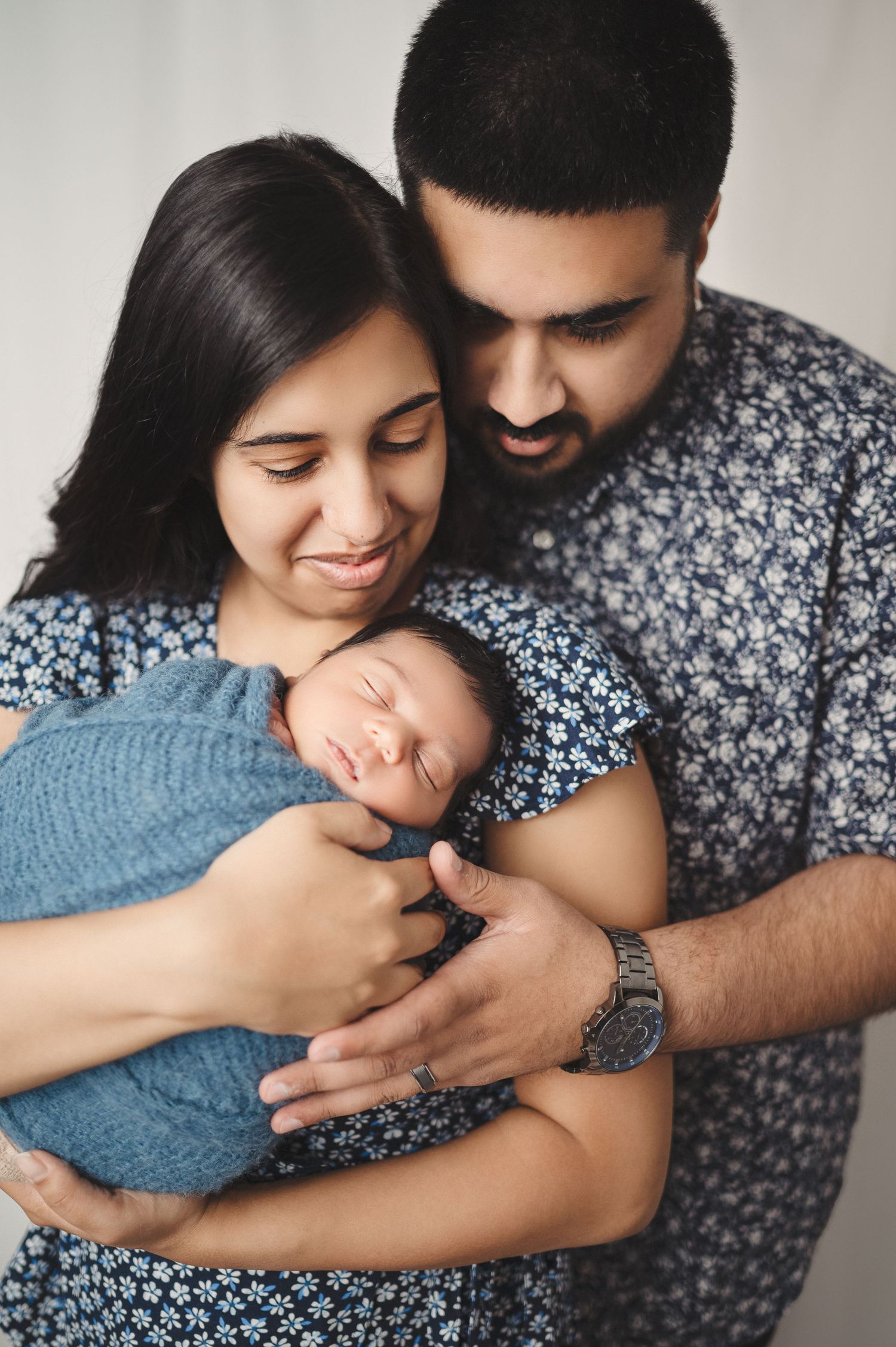 Heartwarming family photo sequence with parents embracing their newborn in blue wrap.