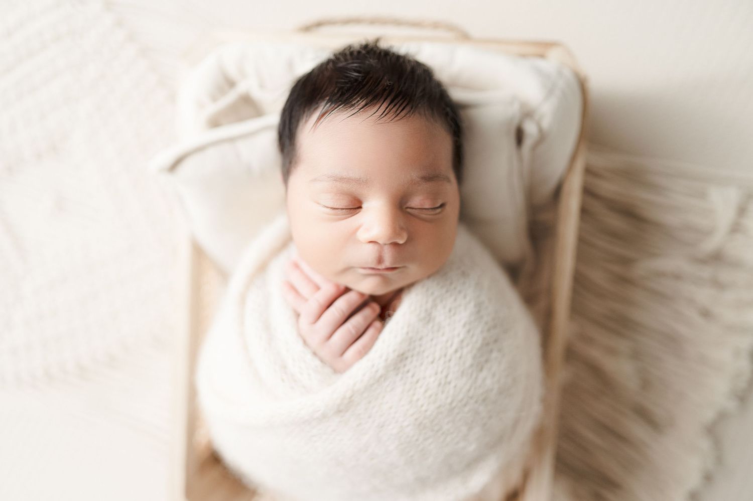 Close-up of peaceful newborn baby wrapped in white swaddle.