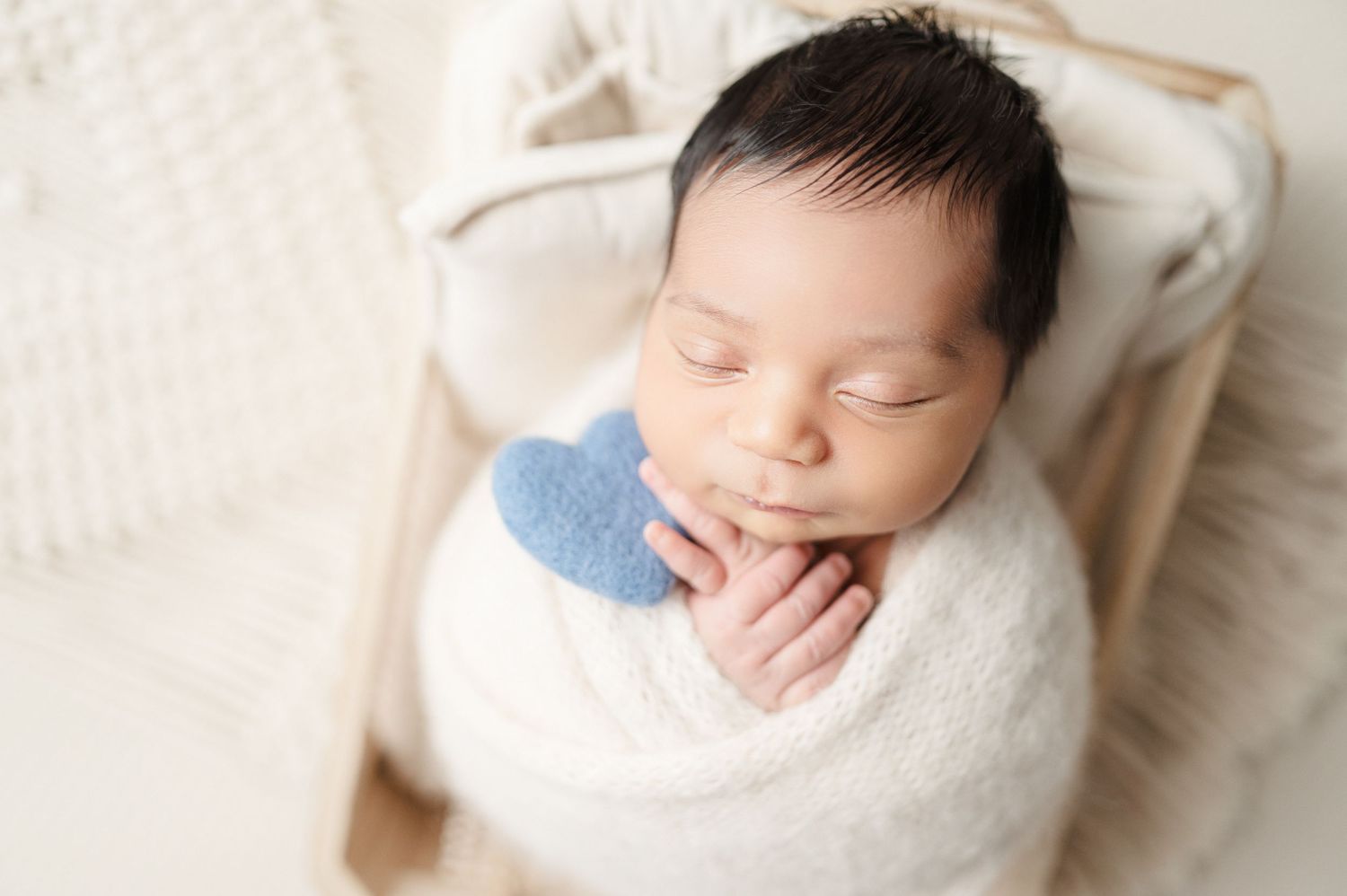Newborn baby in side-lying position with white wrap during studio photography session.
