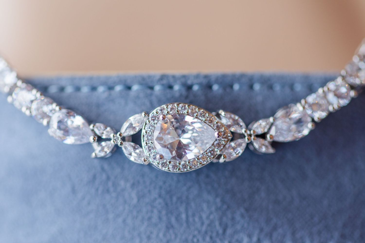 Elegant crystal bracelet with teardrop center stone on blue velvet.