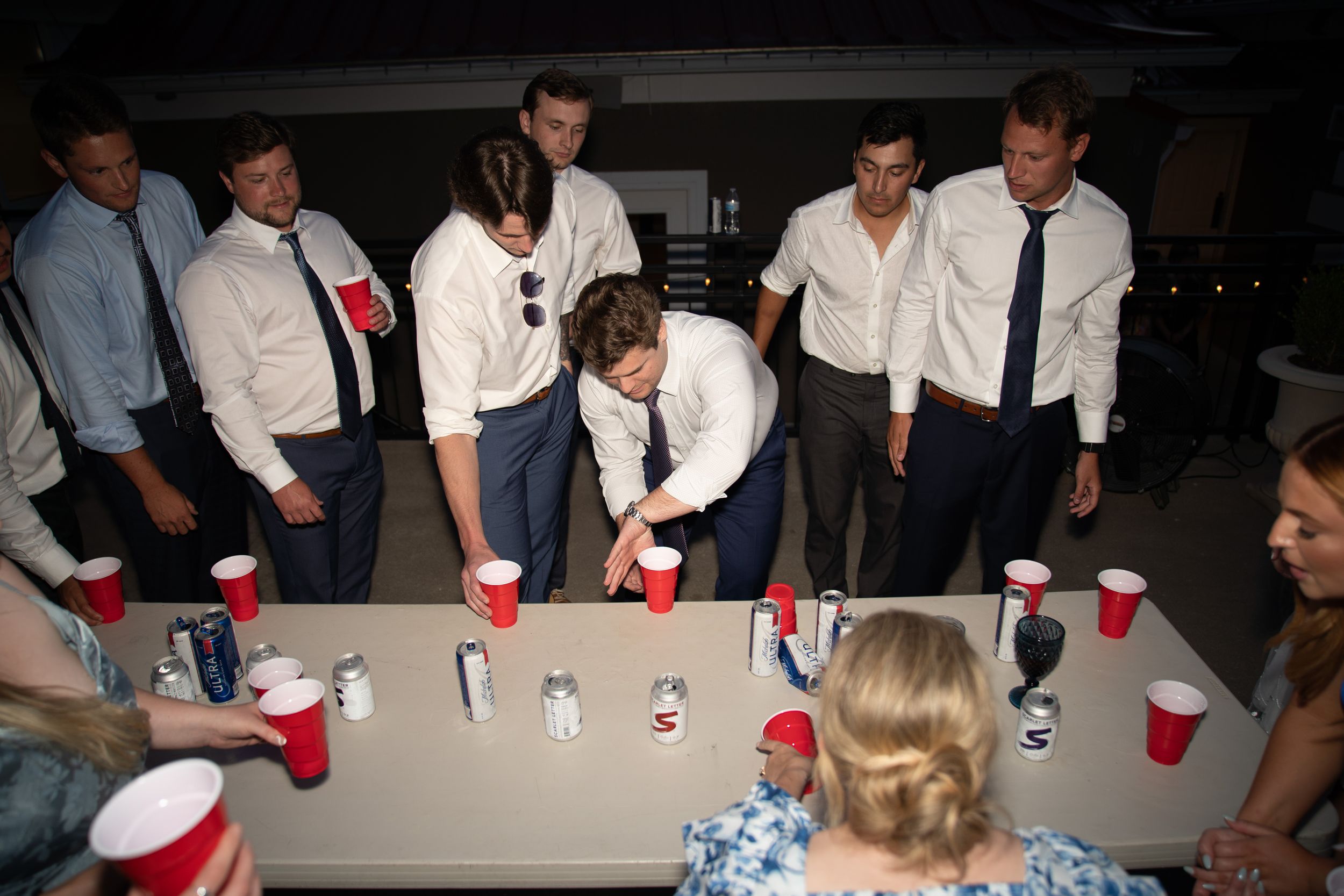 Wedding reception party with red solo cups on tables in evening lighting.