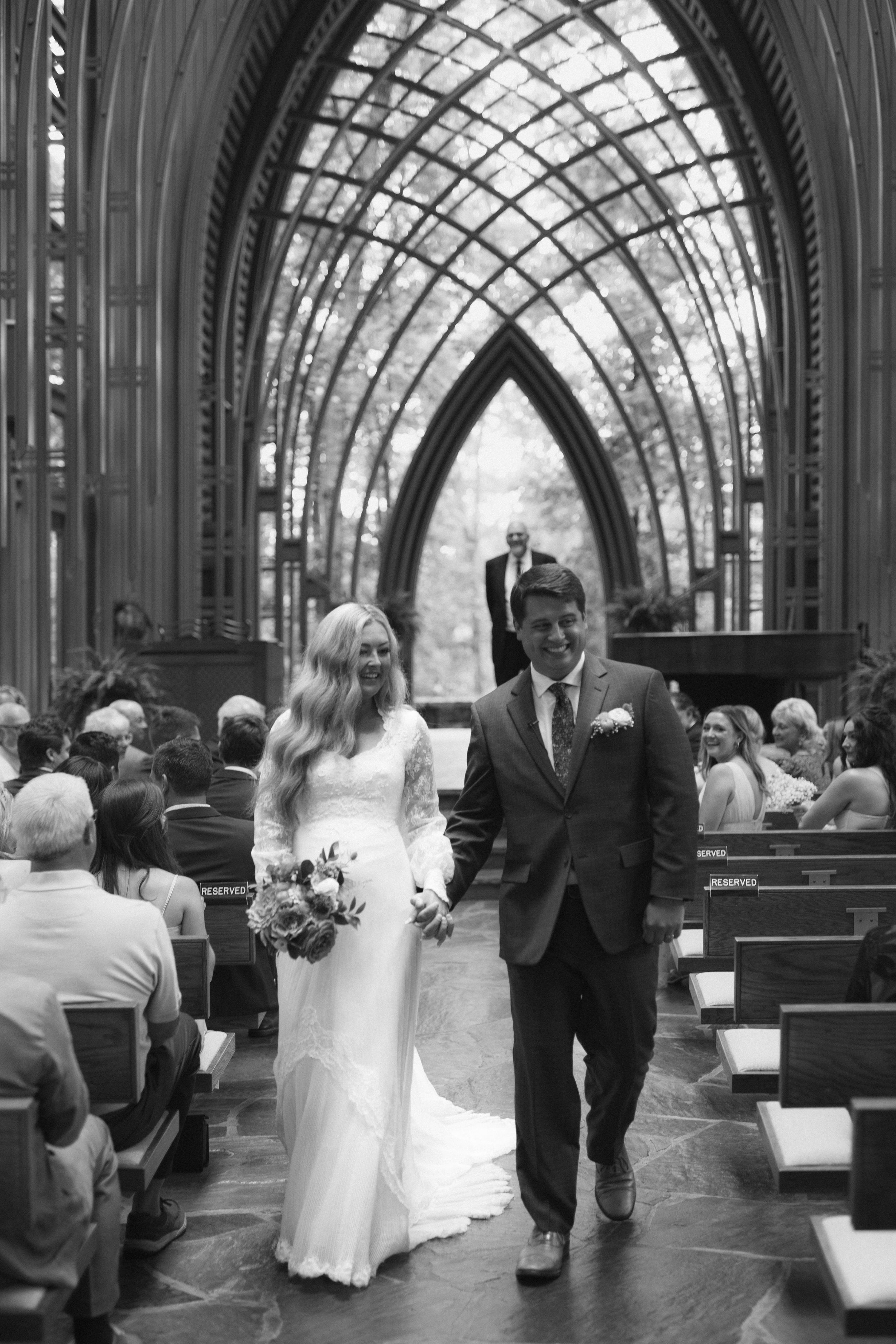 Couple walking through a beautiful Gothic church interior with arched ceilings during their wedding ceremony.
