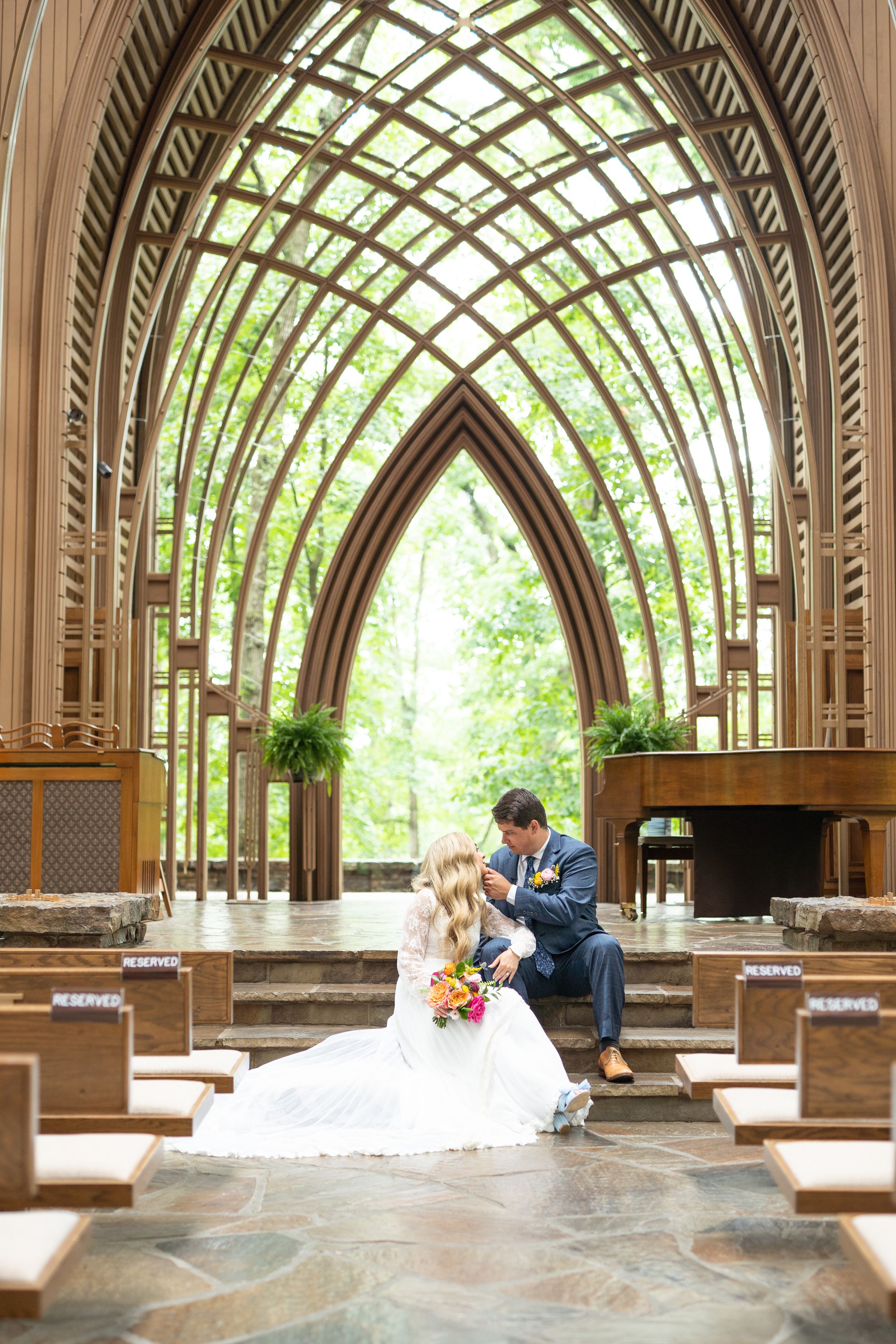 Wooden chapel interior with architectural arches and natural lighting through lattice ceiling.