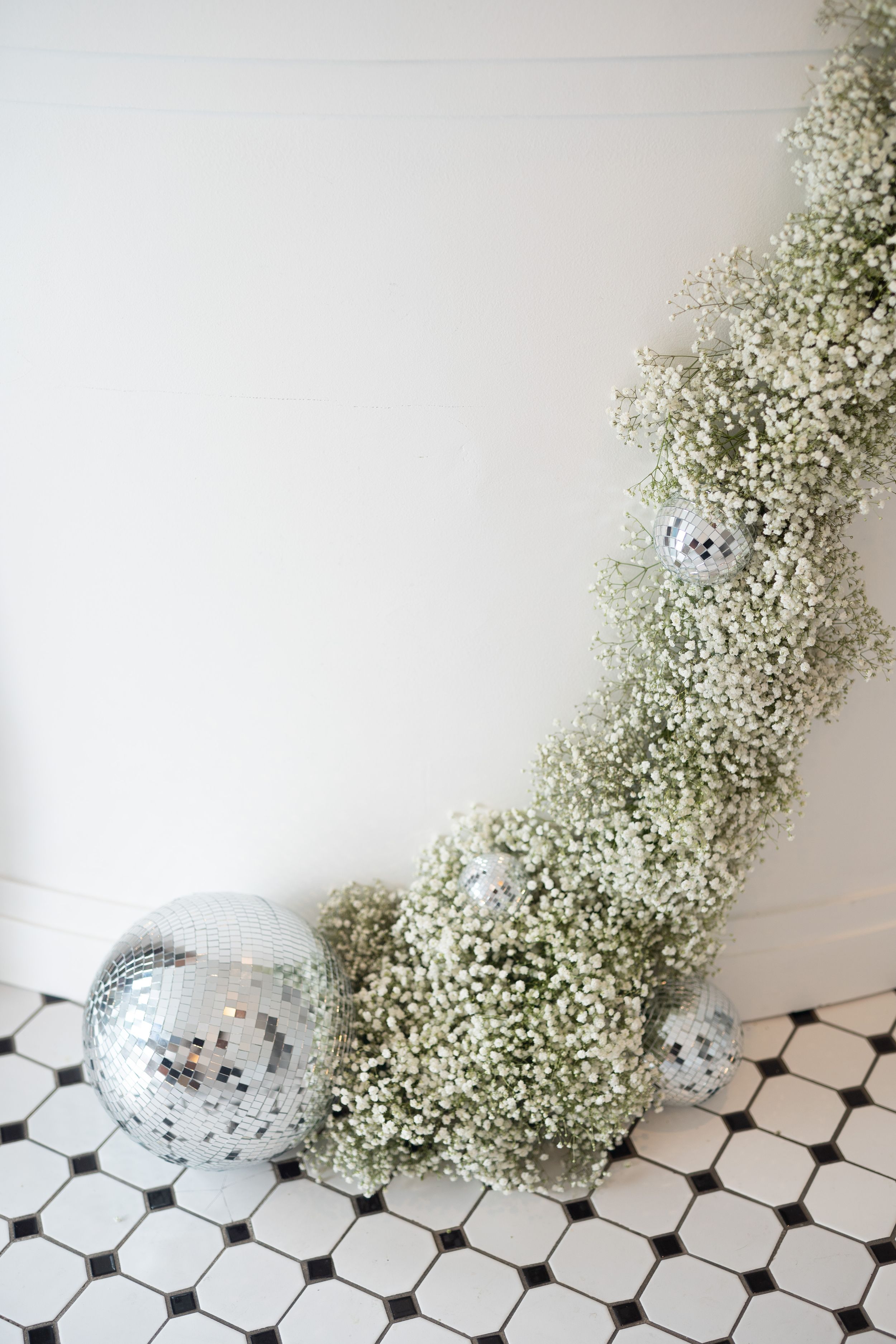 Baby's breath flowers and disco balls arranged on black and white checkered flooring.