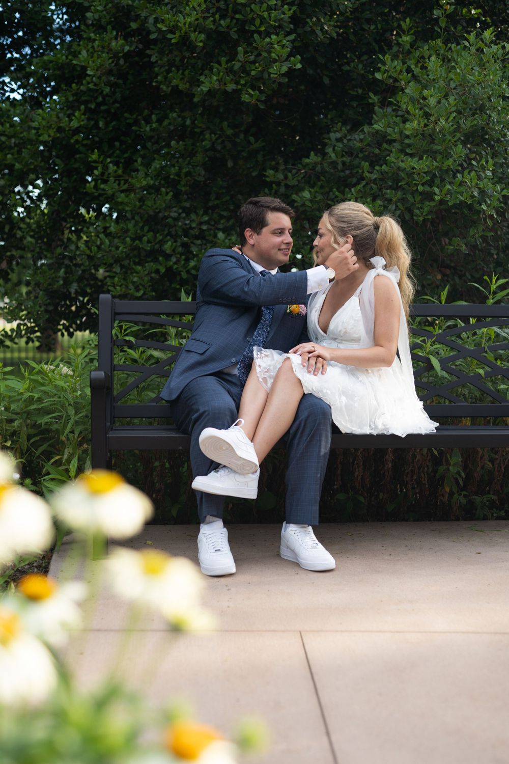 Romantic couple sharing a moment on a park bench surrounded by greenery.