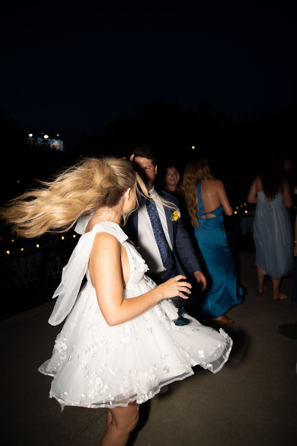 A white dress swirls in motion during nighttime dancing at an event.