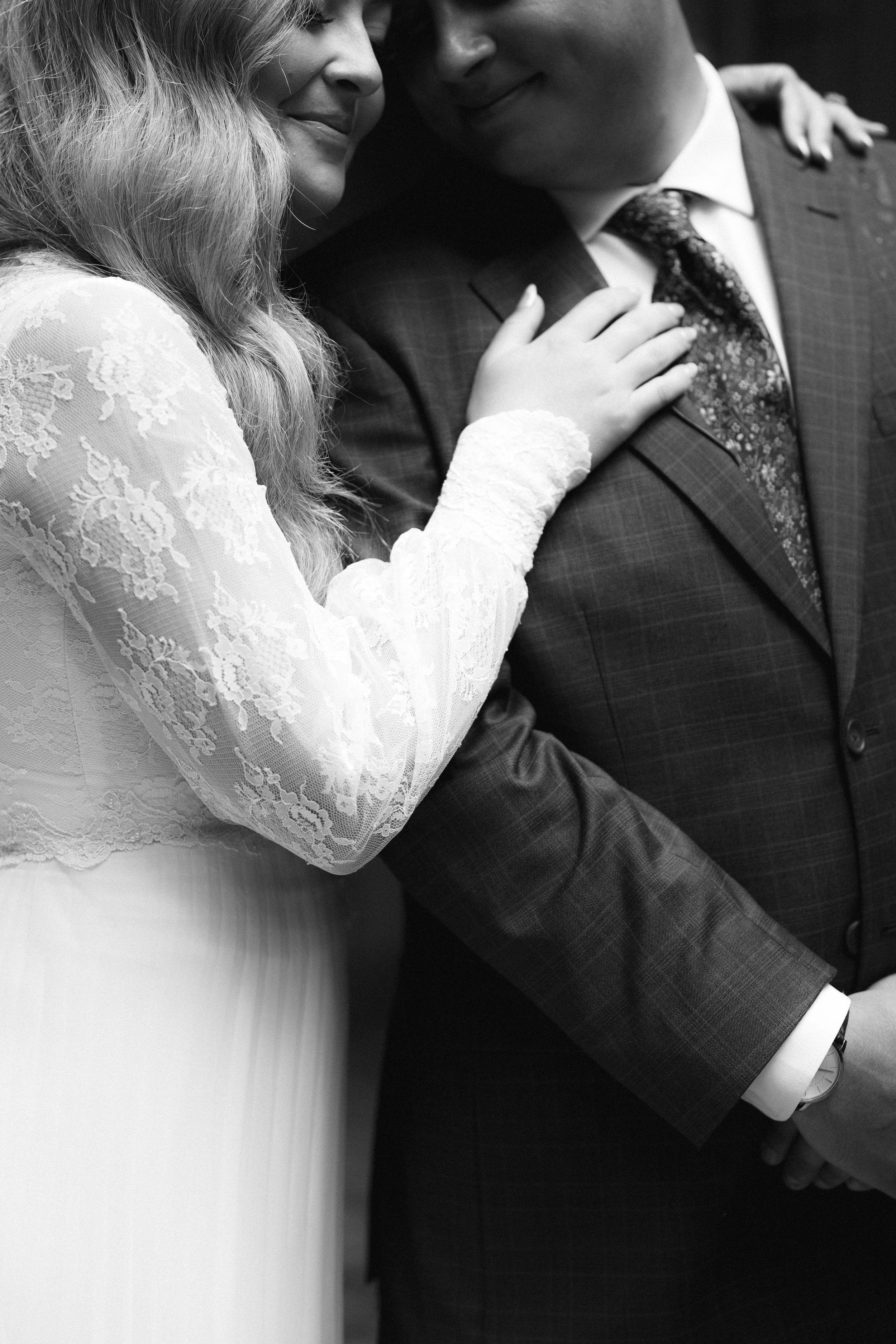 Intimate black and white wedding portrait showing close embrace in formal attire.