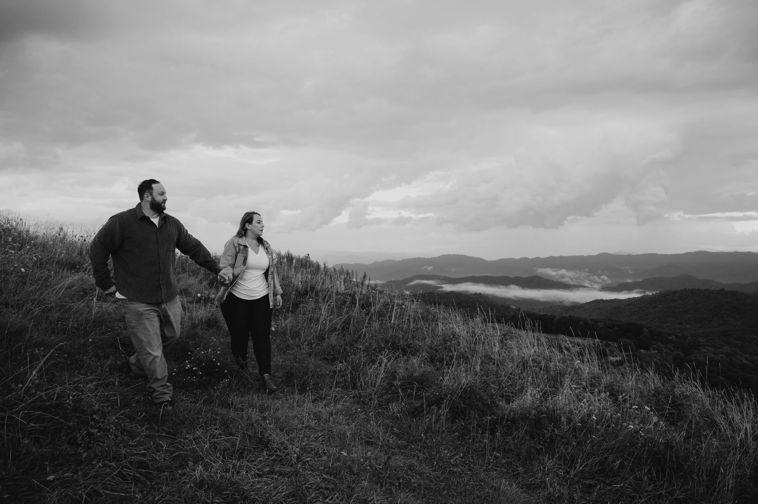 A black and white landscape photo of a couple enjoying a scenic mountain vista together.