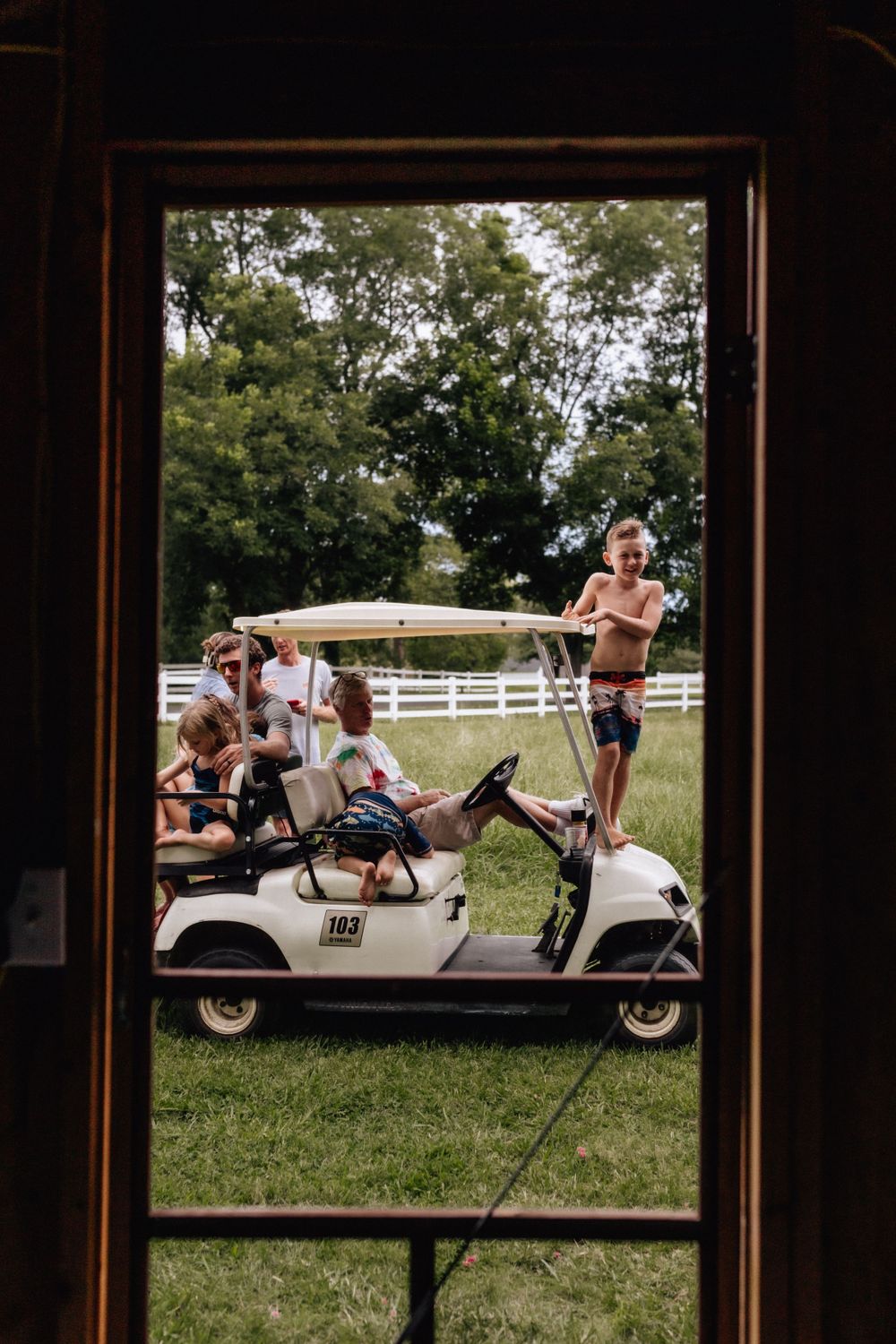 kids hanging off a golf cart framed by a doorway
