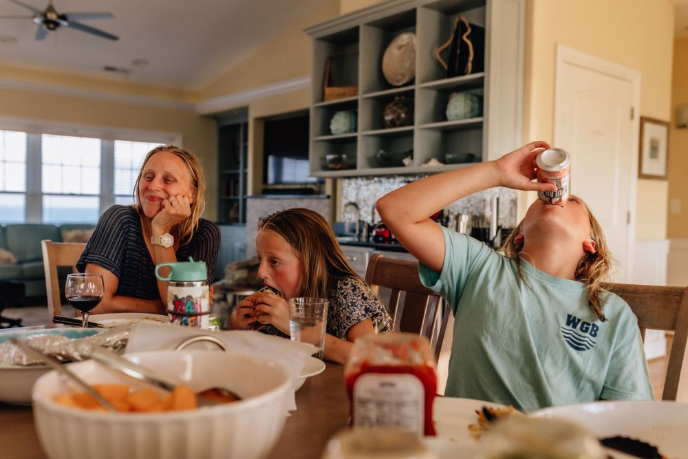 girls eating dinner at the kitchen table at their vacation home in sandbridge beach, virginia and drinking a can of coke