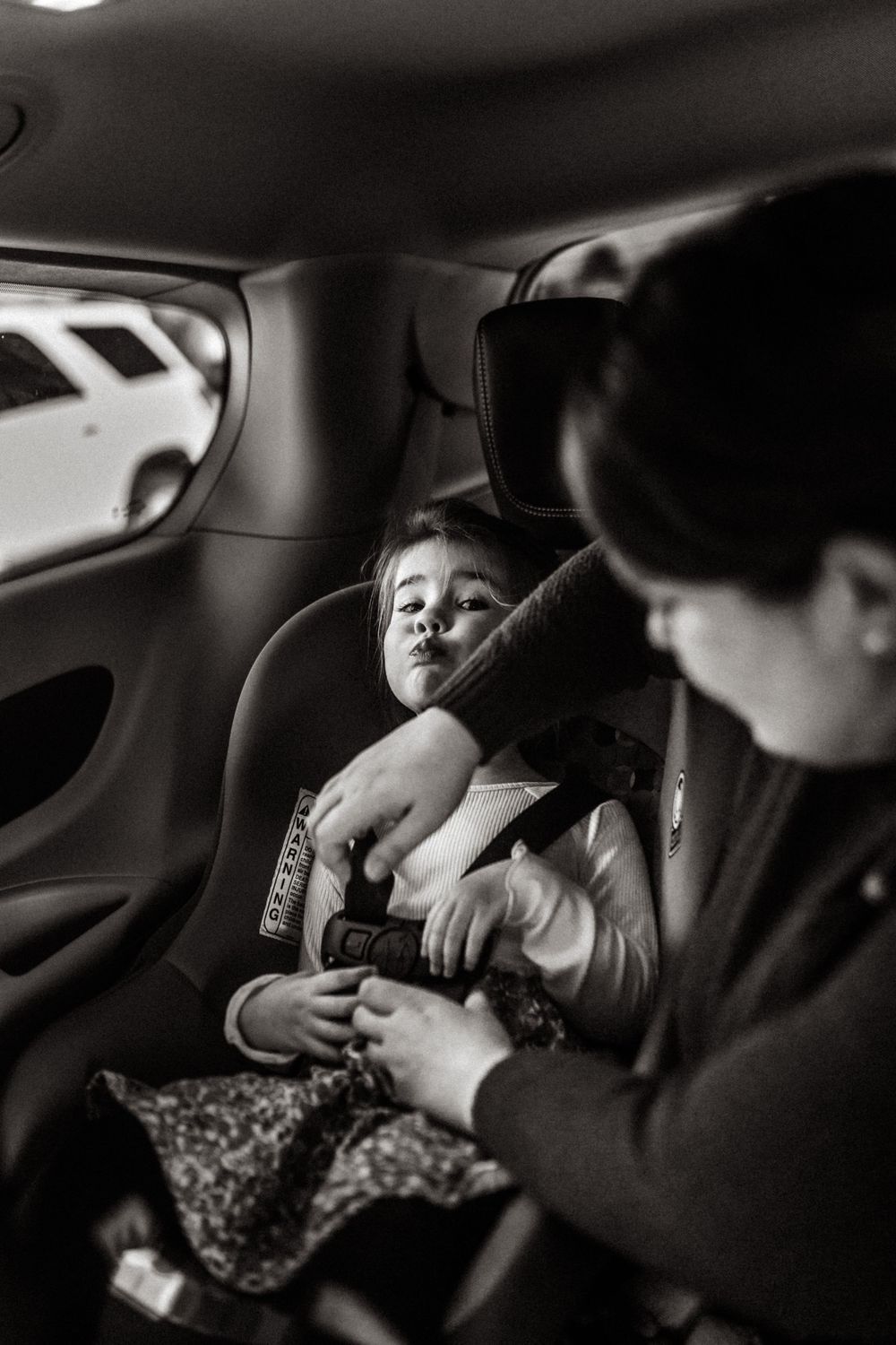 mom buckling toddler into a car seat