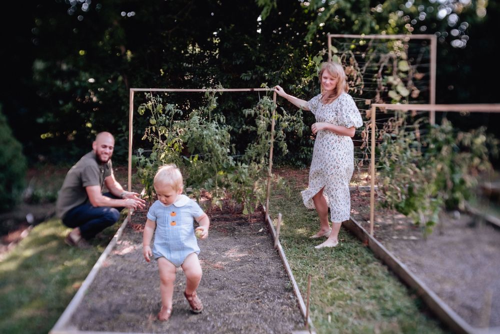 family standing in the vegetable garden with their toddler