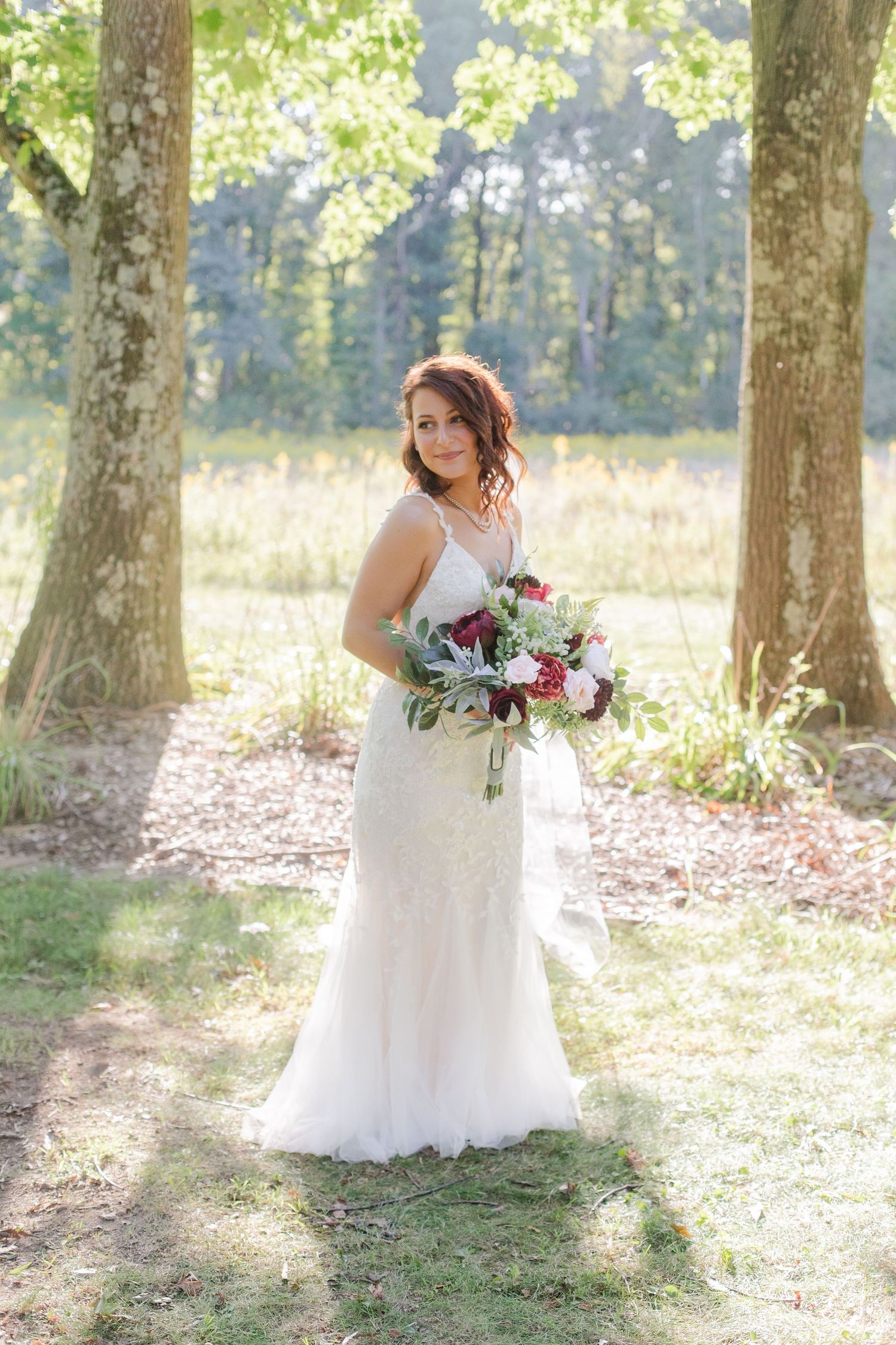 Bridal portraits in a sunlit wooded area with scattered autumn leaves.