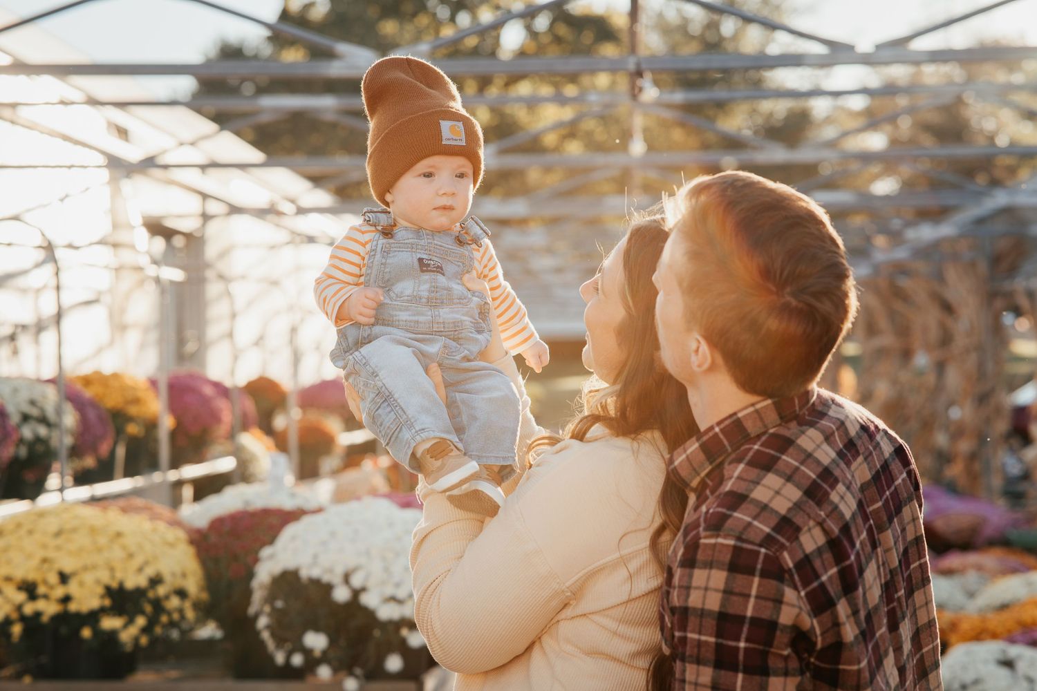 Family enjoying a sunny moment at a garden nursery with autumn decorations.