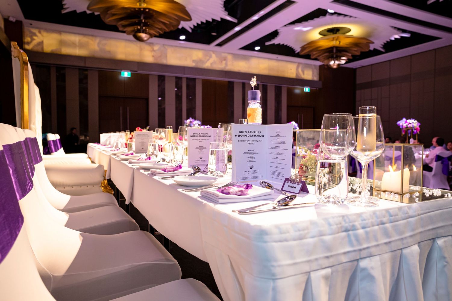 Elegant banquet hall setup with white table settings and purple accent lighting creating an upscale atmosphere.