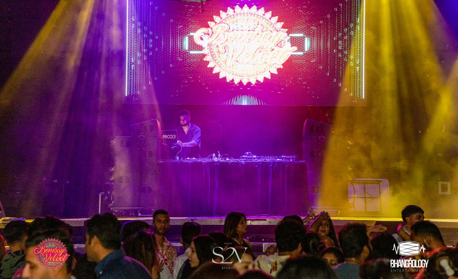 Concert venue with colorful purple and yellow stage lighting creating a vibrant atmosphere.