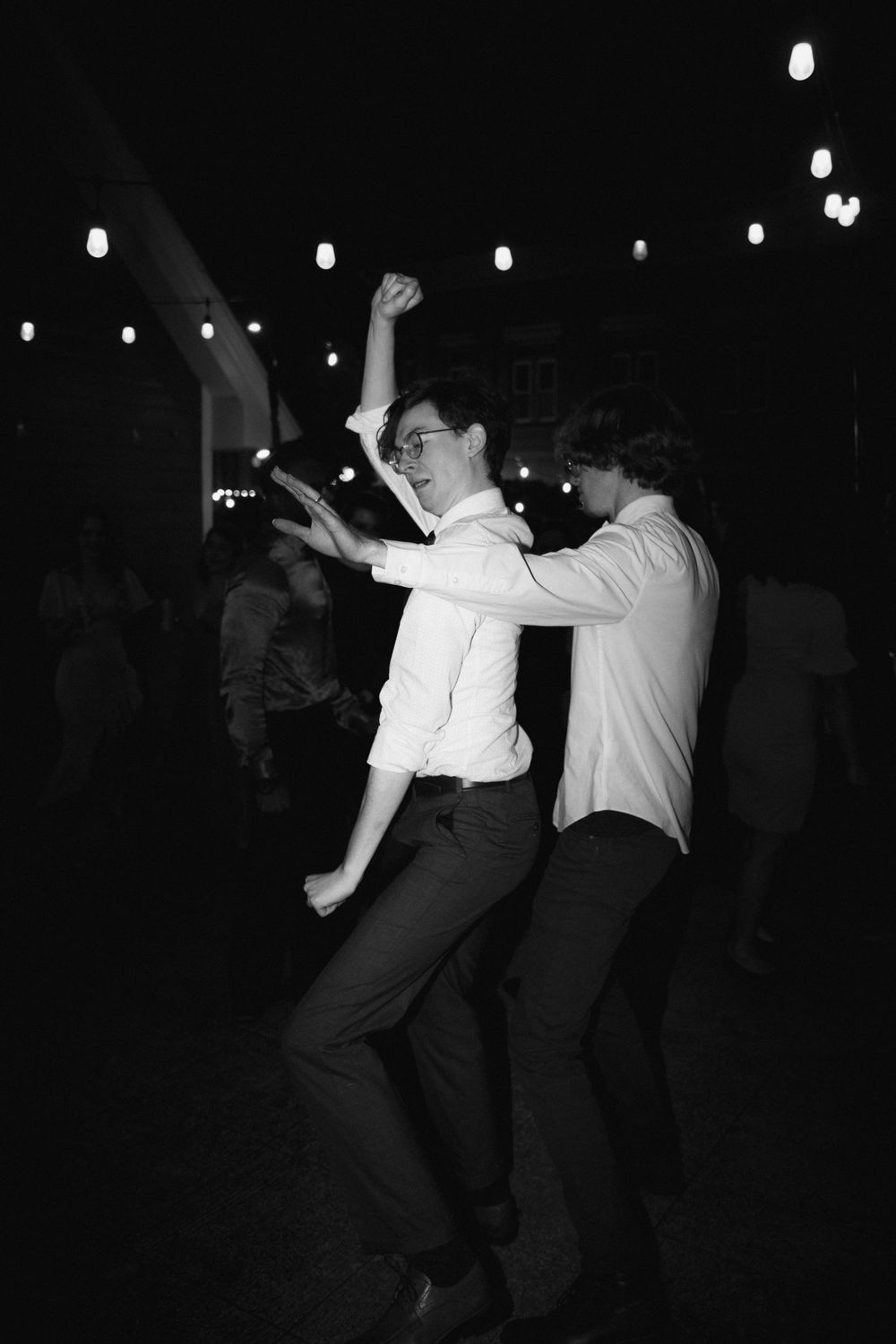 Black and white photo of energetic dancing at a wedding reception.