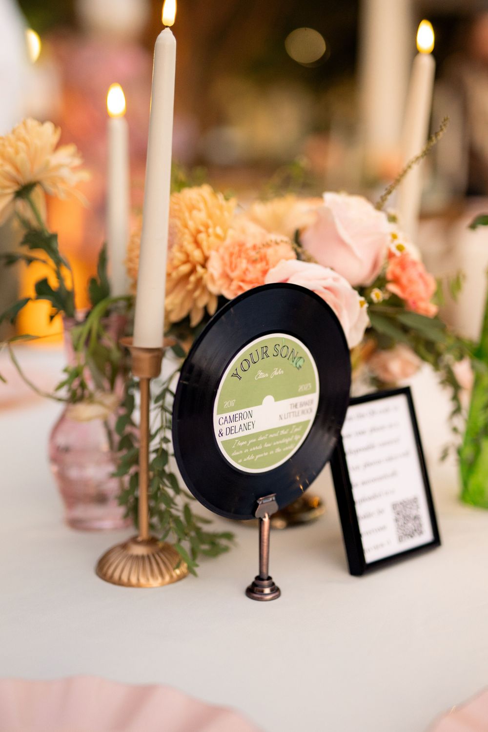 Wedding table decor featuring vintage vinyl record, taper candles, and peachy floral centerpieces.