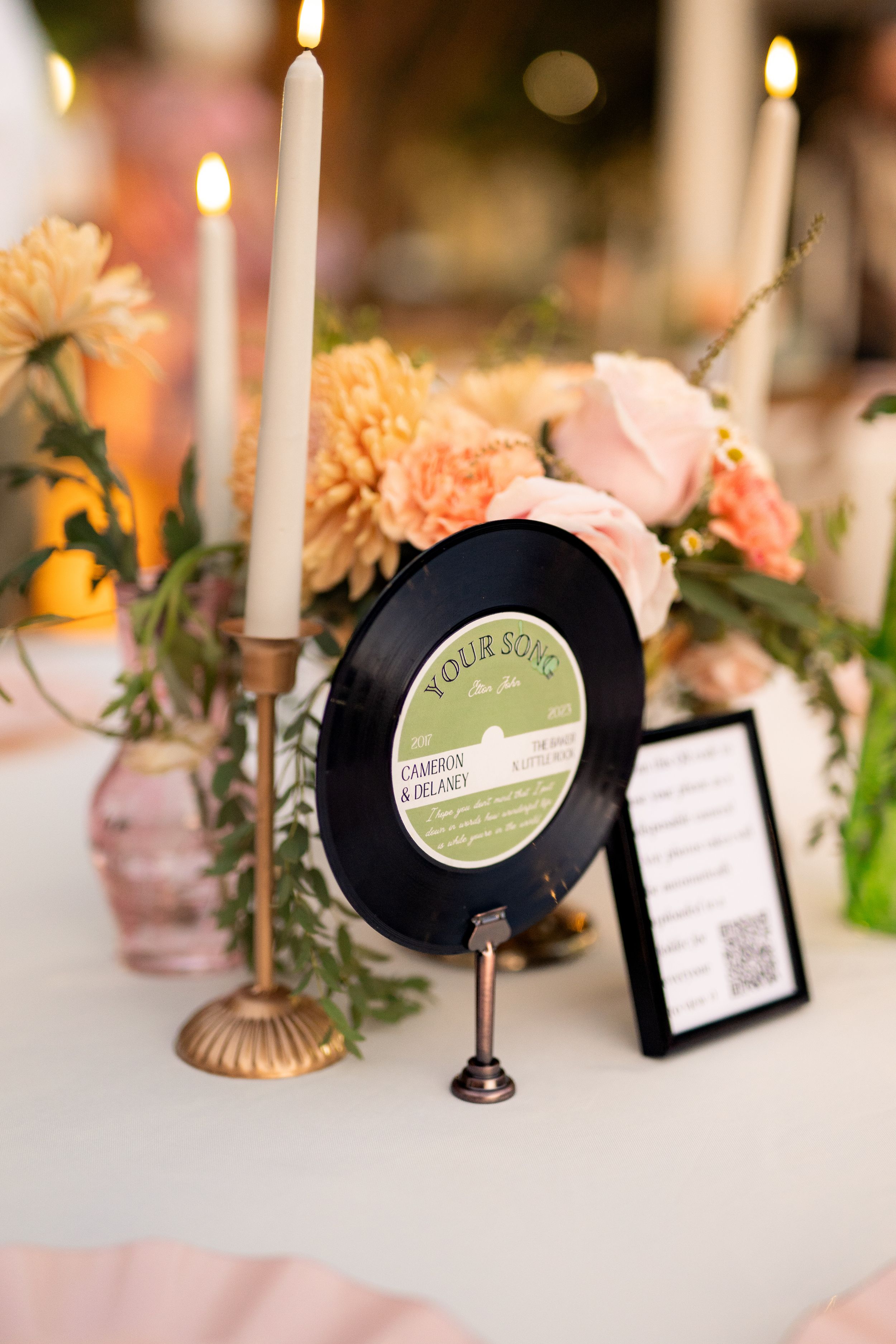 Wedding table decor featuring vintage vinyl record, taper candles, and peachy floral centerpieces.
