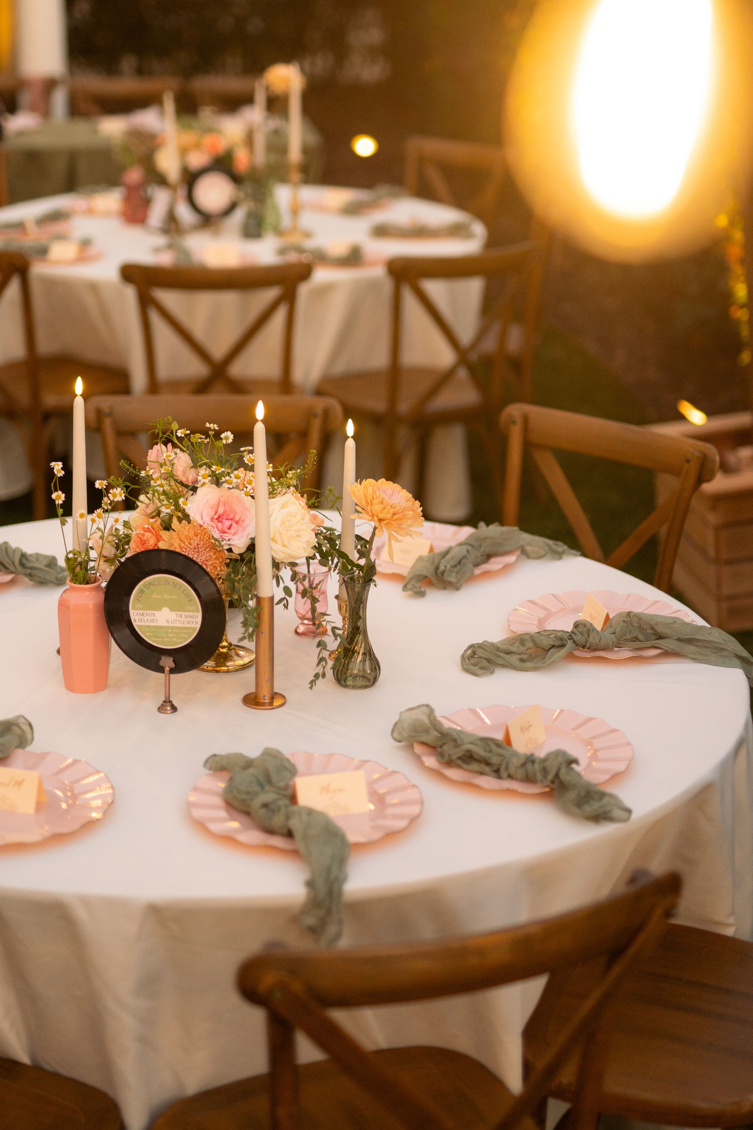 Romantic table setting with vinyl records, candles, and pink floral arrangements at wedding reception.