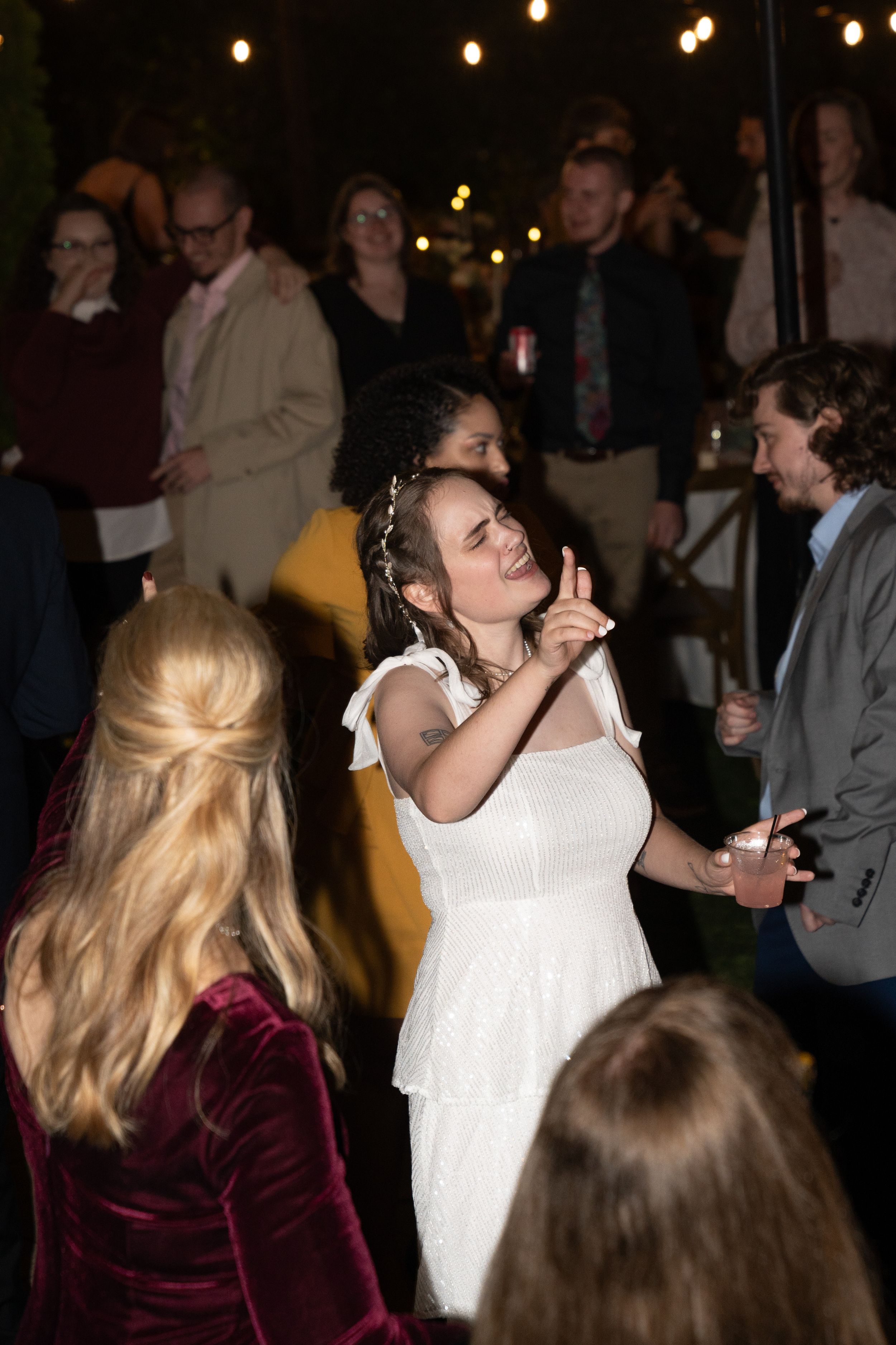 Wedding reception dance floor filled with celebrating guests under string lights.