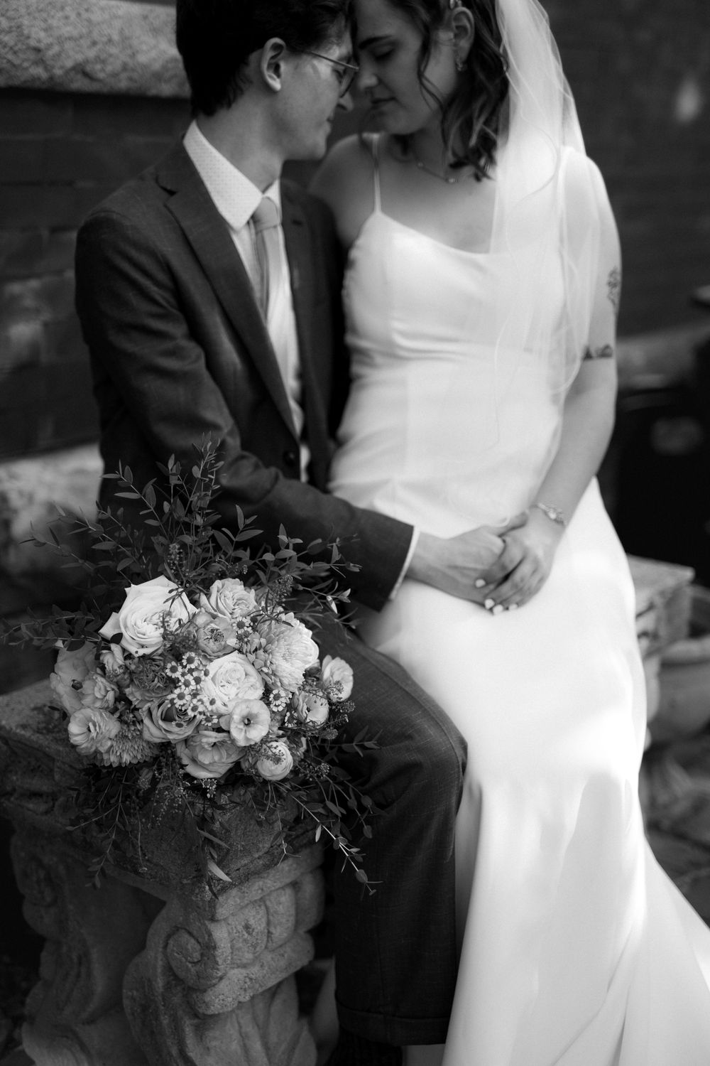 Black and white wedding portrait with elegant floral bouquet details.