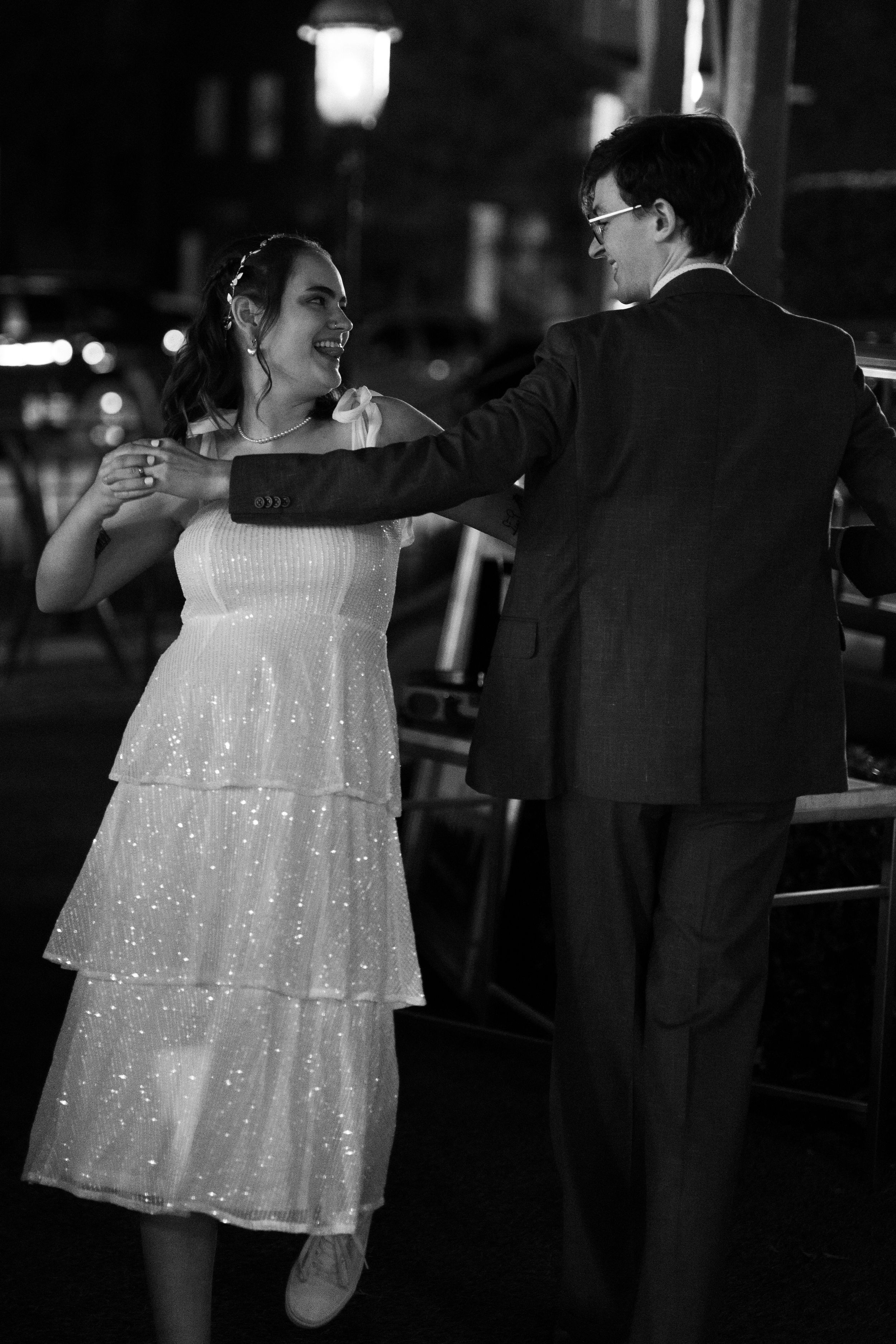 A sparkling white party dress twirls on a dark dance floor.