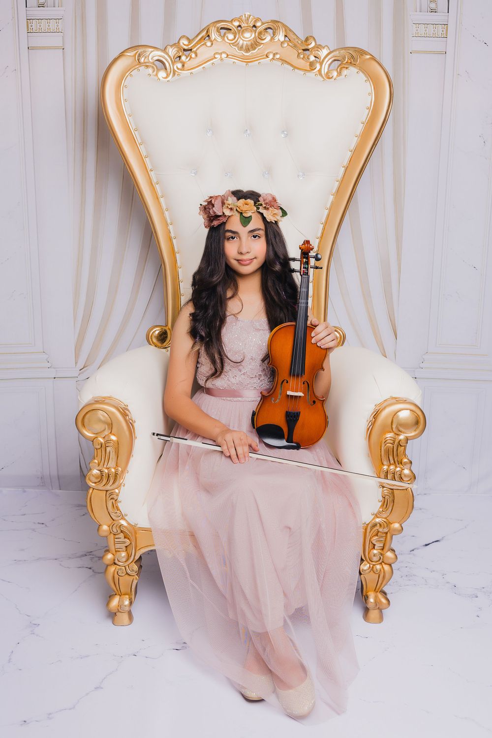 Elegant portrait with violin on ornate white and gold throne chair.