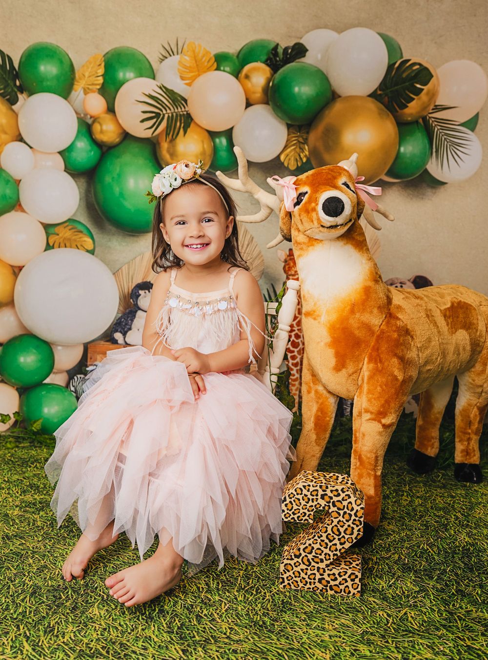 Safari themed photo setup with stuffed deer and balloon arch decorations.