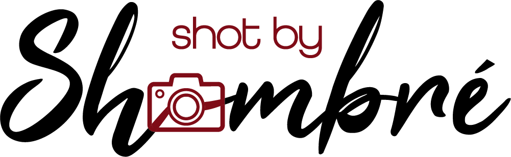 Red neon text reading 'shot by' with camera icon on black background.