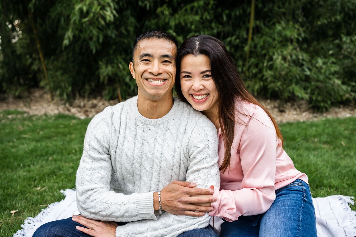 Husband and wife sitting on a blanket smiling