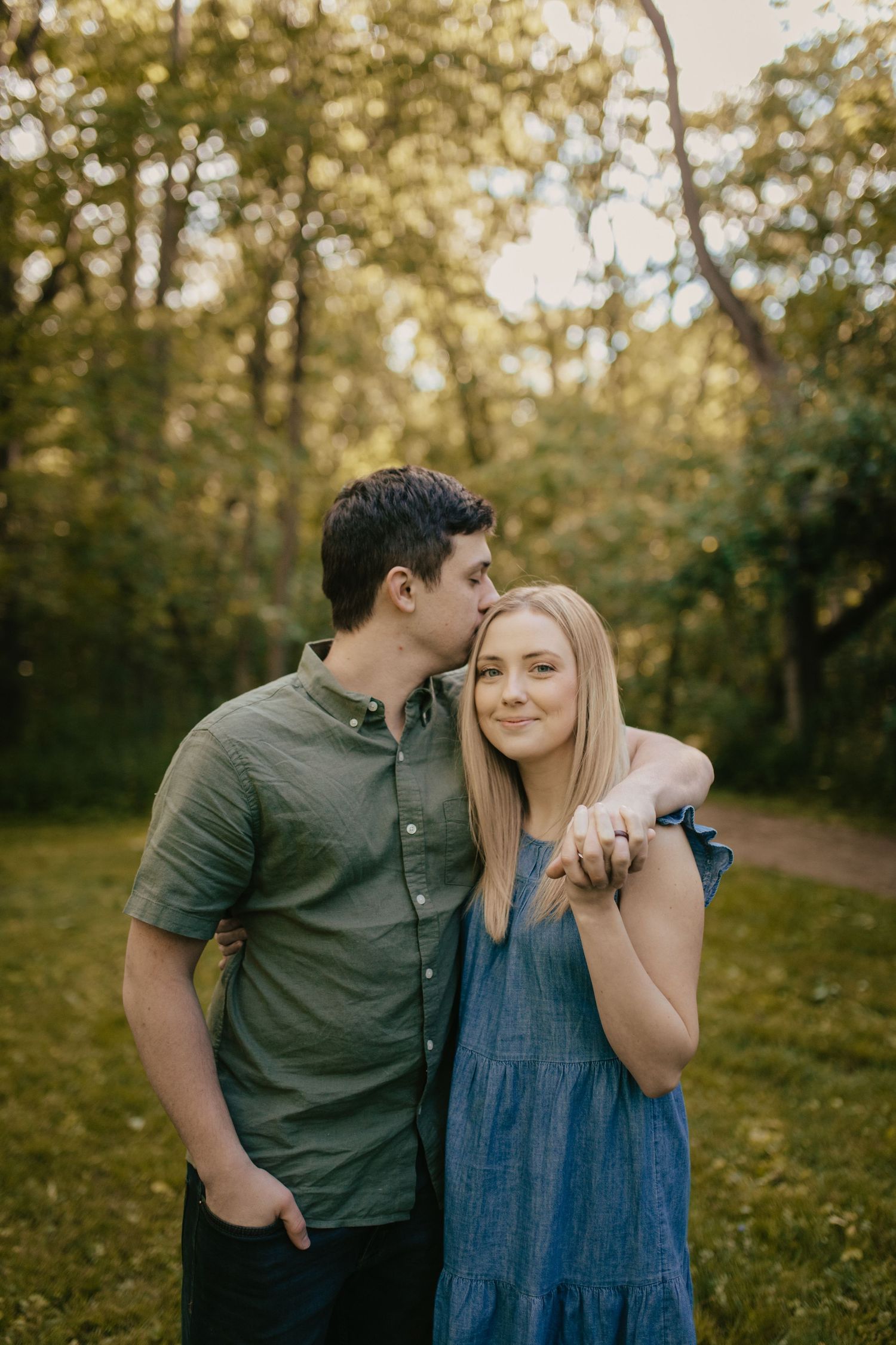 Couple embraces in a sunlit wooded area during autumn.