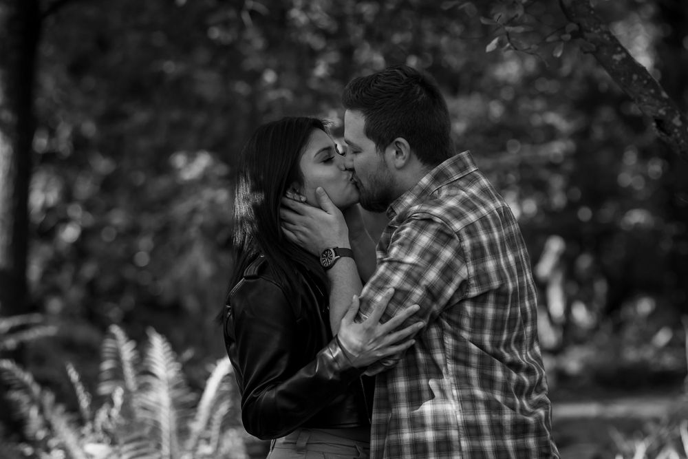 A black and white photo captures an intimate moment between a couple on a scenic garden path.