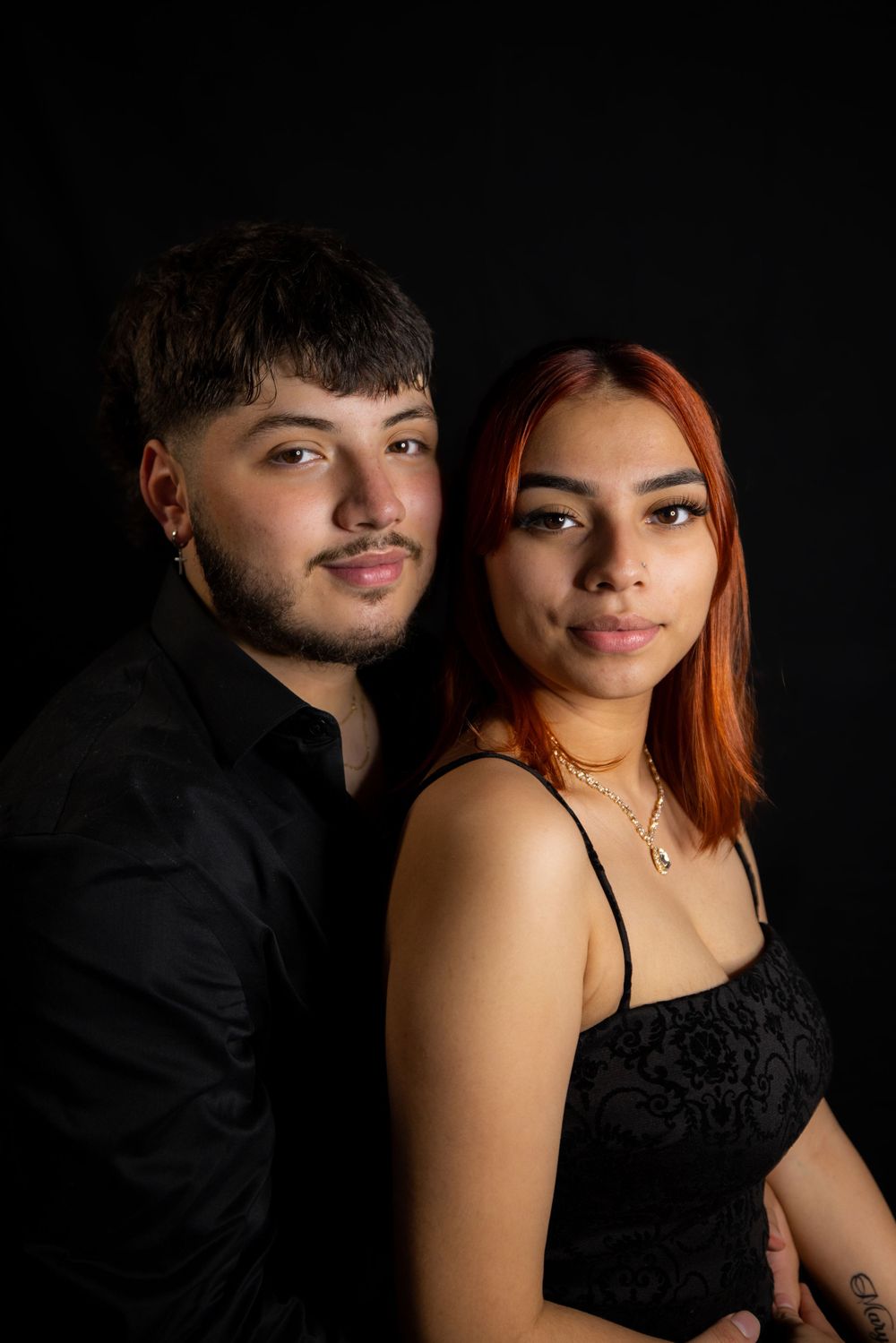 Stylish couple posing for a studio portrait against black backdrop.