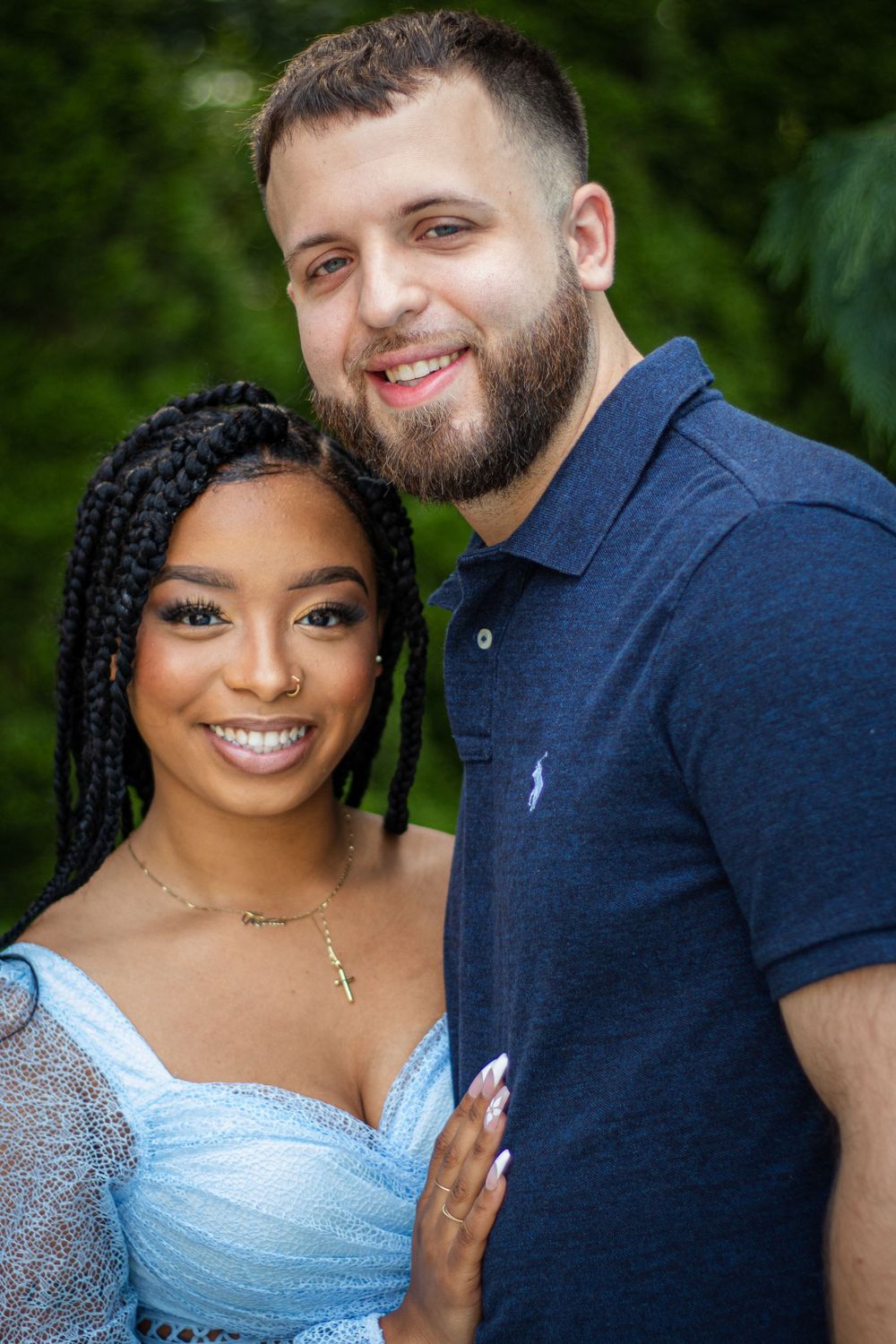 Couple smiles together in outdoor portrait with natural greenery.