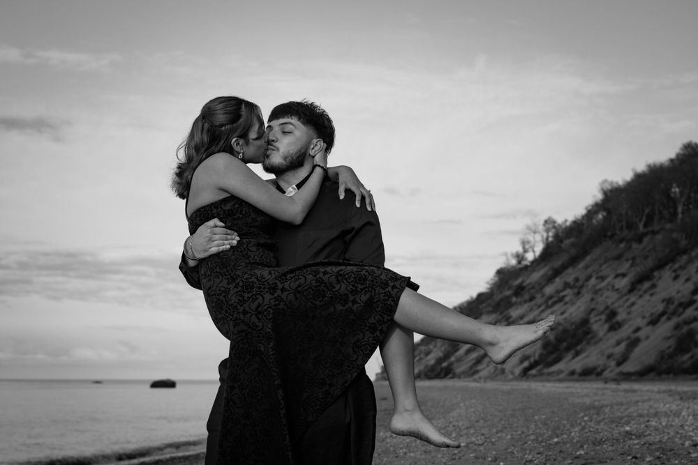 Romantic couple sharing an intimate moment while embracing on a beach at sunset.