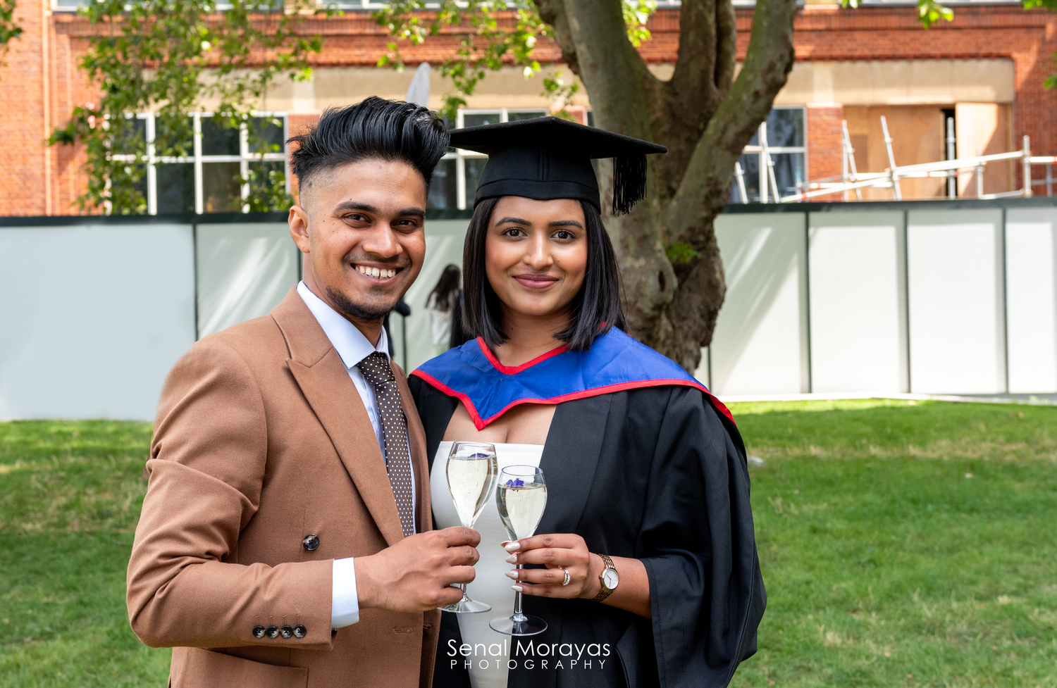 Graduation celebration photoshoot in an outdoor setting with academic regalia.
