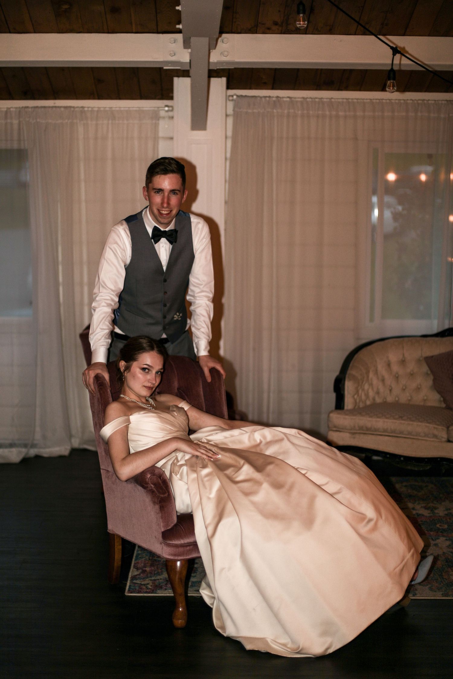 Stylish wedding portrait with couple posing on vintage furniture.