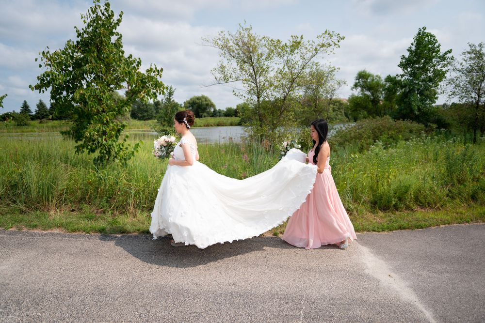 Wedding dress train creates elegant silhouette against outdoor pathway.