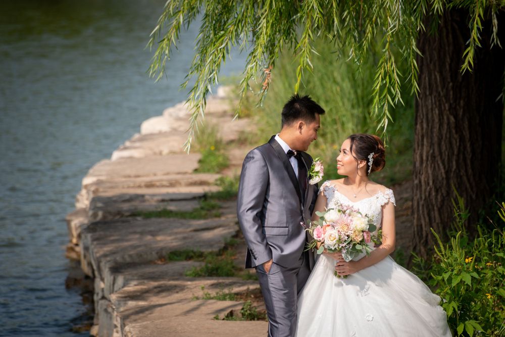 A couple shares an intimate moment on a stone pathway beside a serene lake.