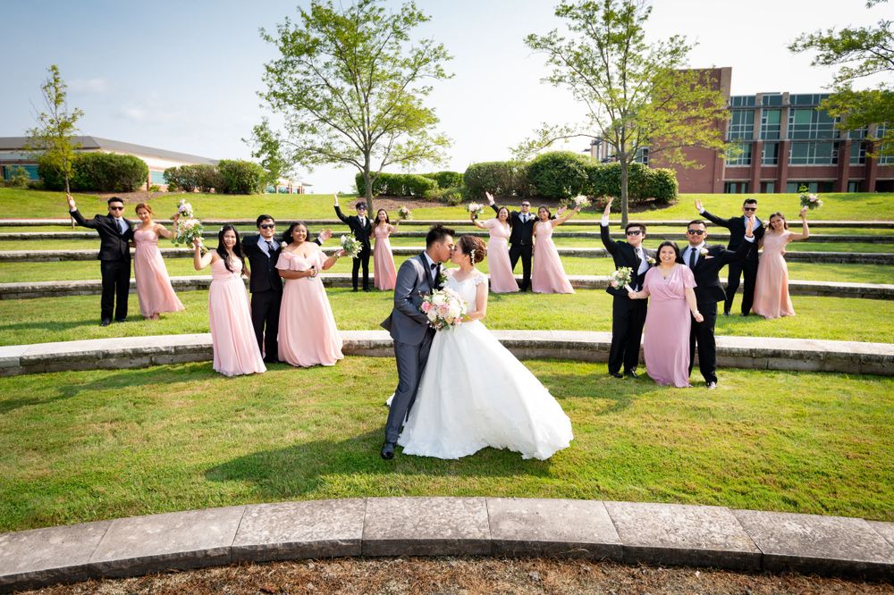 Wedding party poses together on a lush green lawn during an outdoor celebration.