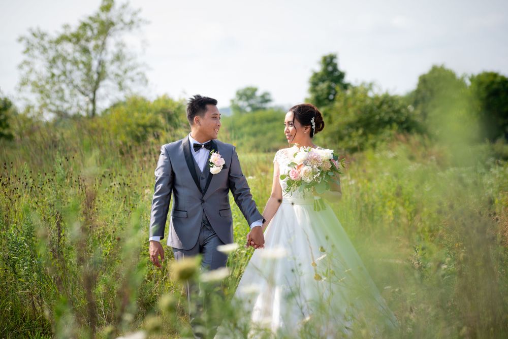 Elegant wedding party celebrates in a scenic outdoor garden setting with spring greenery.