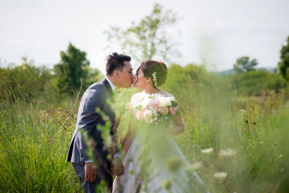 Romantic wedding moments photographed through wildflowers in a natural outdoor setting.