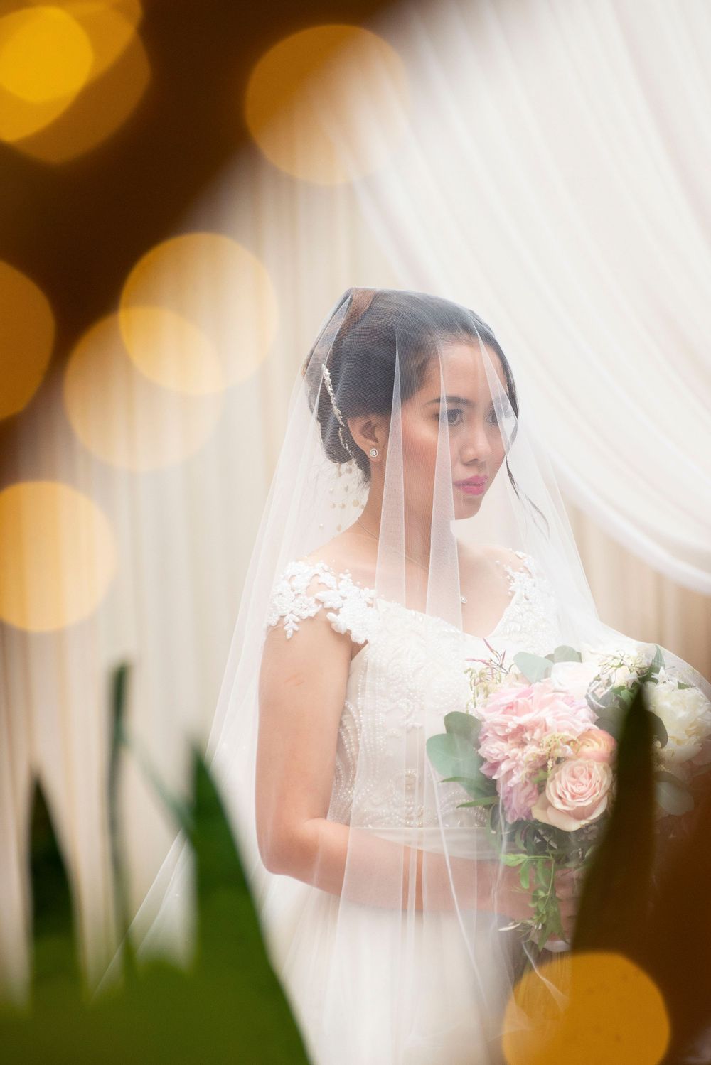 Ethereal bridal portrait with soft bokeh lighting and delicate veil details.