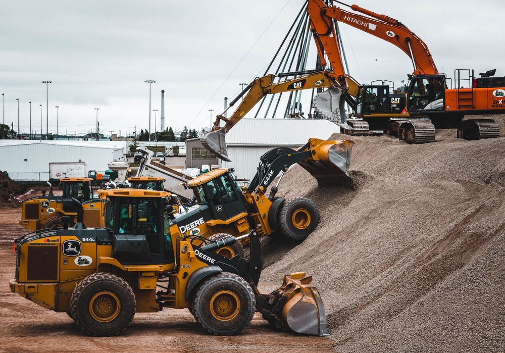 Heavy construction vehicles and wheel loaders operating at gravel processing site.