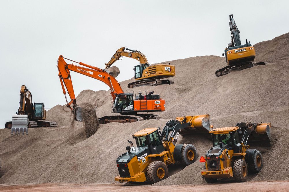 Multiple excavators and construction vehicles operating on a dirt construction site.