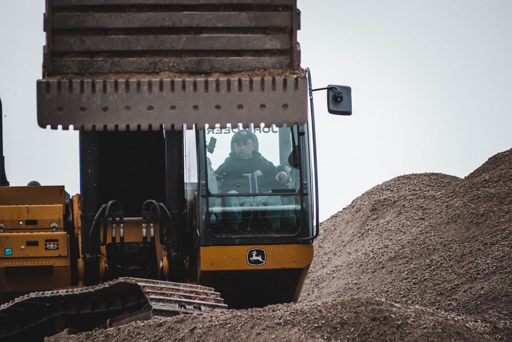 Construction vehicles and equipment positioned on dirt mounds at a work site.