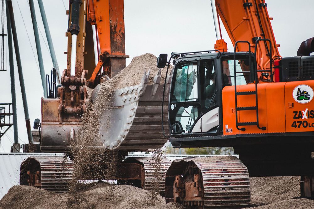 Row of orange excavators and construction equipment at work site.