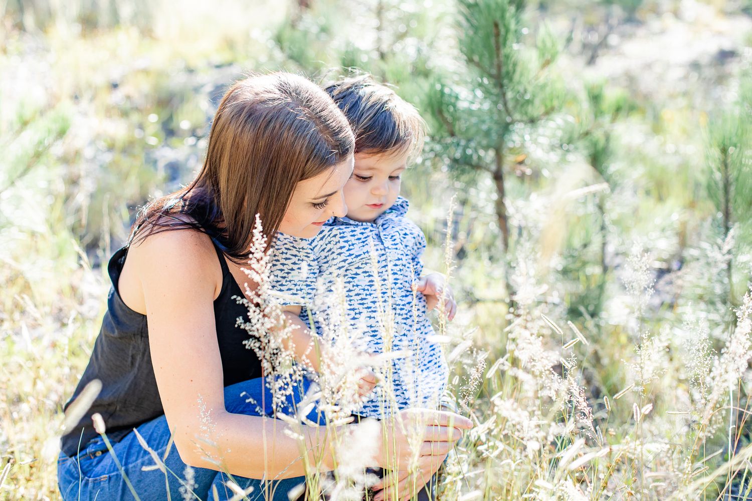 Mom and her toddler boy look at the grass together in Black Forest, Colorado.